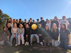 Gruppenfoto einer 8. Klasse im Freien vor Bäumen und blauem Himmel